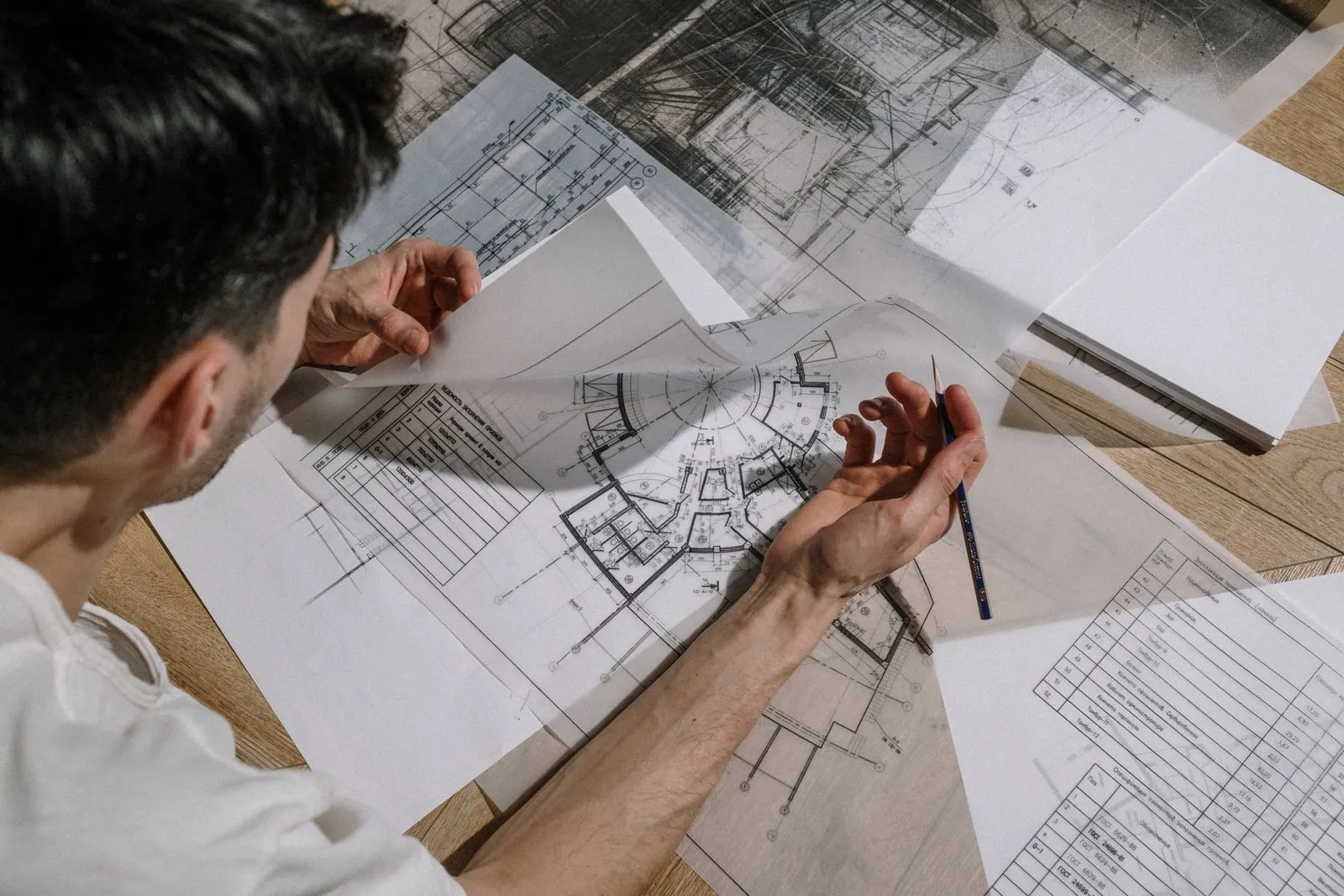 Architect sketching over detailed architectural drawings